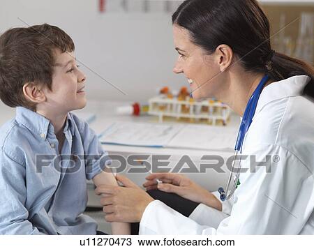 Doctor comforting young boy in clinic View Large Photo Image Stock Image - Doctor comforting young boy in clinic. Fotosearch