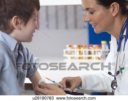 Doctor comforting young boy in clinic View Large Photo Image Stock Image - Doctor comforting young boy in clinic. Fotosearch