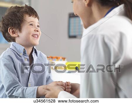 Doctor comforting young boy in clinic View Large Photo Image Stock Photo - Doctor comforting young boy in clinic. Fotosearch