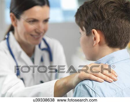 Doctor comforting young boy in clinic View Large Photo Image Stock Photo - Doctor comforting young boy in clinic. Fotosearch