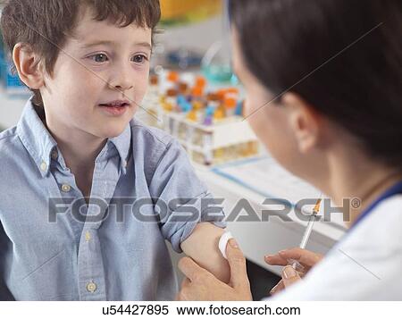 Stock Photography - Doctor comforting young boy in clinic. Fotosearch