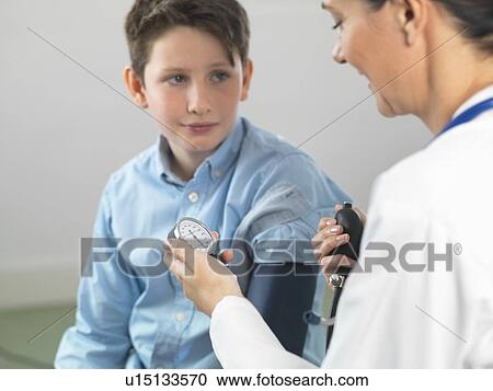 Doctor reading blood pressure of young boy in clinic View Large Photo Image Stock Image - Doctor reading blood pressure of young boy in clinic. Fotosearch