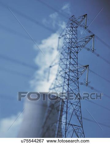 Stock Photo - "Electricity pylon at power station against blue sky, low angle view". Fotosearch