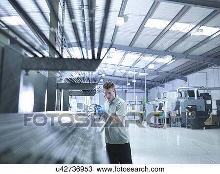 Engineer apprentice inspecting steel rods in factory View Large Photo Image Stock Image - Engineer apprentice inspecting steel rods in factory. Fotosearch