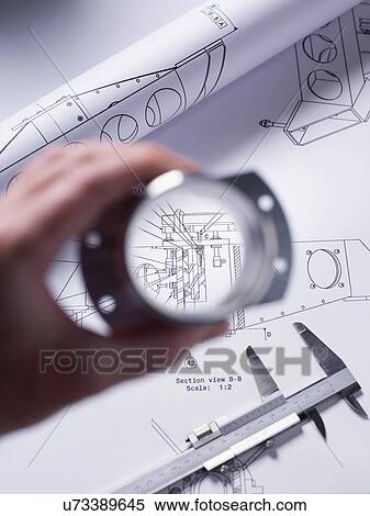 Stock Photography - Engineer holding a precision made component over a technical drawing with a dial caliper. Fotosearch