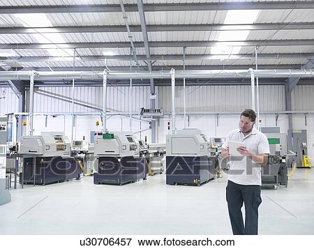 Engineer using digital tablet by production line in factory View Large Photo Image Stock Photo - Engineer using digital tablet by production line in factory. Fotosearch