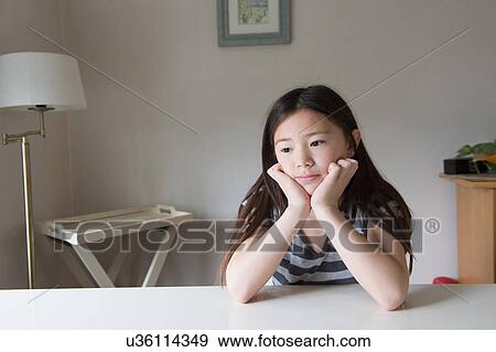 Fed up girl at table with chin in hands View Large Photo Image Stock Photo - Fed up girl at table with chin in hands. Fotosearch