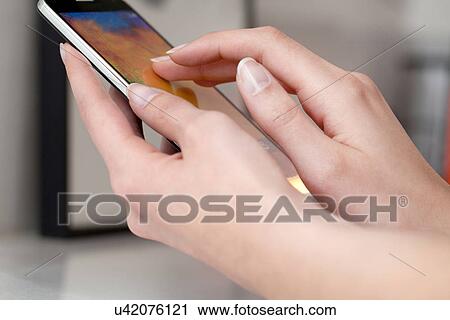 Stock Image - Female hands using smartphone. Fotosearch