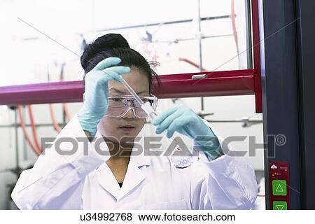 Stock Photo - Female scientist using pipette and volumetric flask in lab. Fotosearch