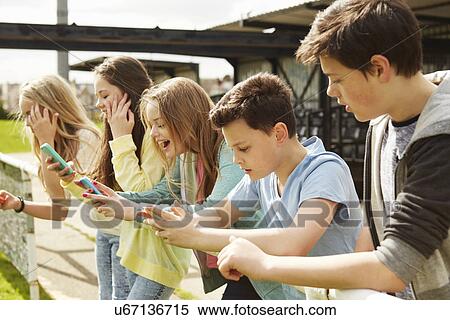 Five girls and boys in stadium stand reading smartphones View Large Photo Image Stock Photography - Five girls and boys in stadium stand reading smartphones. Fotosearch