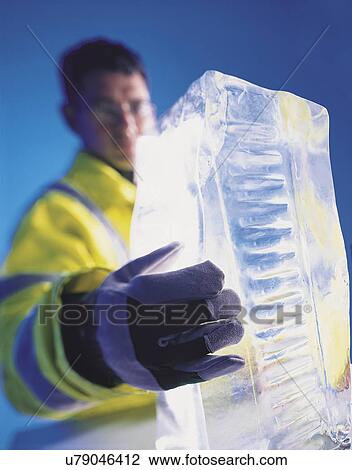 Stock Image - "Food worker holding block of ice, close up". Fotosearch