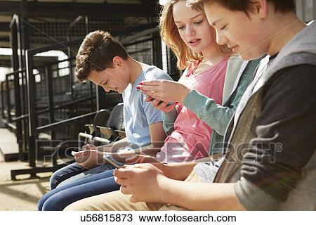 Four boys and girls reading smartphone texts in stadium stand View Large Photo Image Stock Image - Four boys and girls reading smartphone texts in stadium stand. Fotosearch