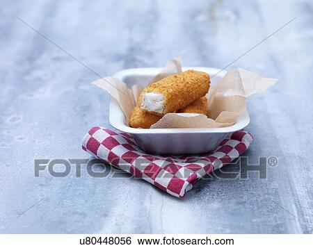 Stock Photograph - Fried chunky breaded cod fish fingers in baking tin on steel table. Fotosearch