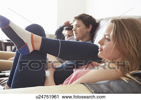 Stock Image - Girl and two boys watching tv from sofa. Fotosearch
