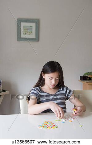 Stock Photo - Girl at table playing with puzzle. Fotosearch