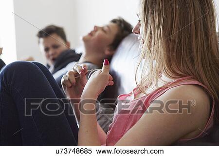 Girl fiddling with earphones on sofa View Large Photo Image Stock Photography - Girl fiddling with earphones on sofa. Fotosearch