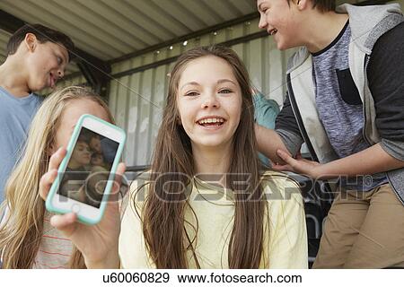 Girl holding up smartphone selfie of friends in shelter View Large Photo Image Stock Photo - Girl holding up smartphone selfie of friends in shelter. Fotosearch
