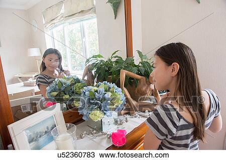 Girl looking in mirror and fiddling with her hair View Large Photo Image Stock Image - Girl looking in mirror and fiddling with her hair. Fotosearch