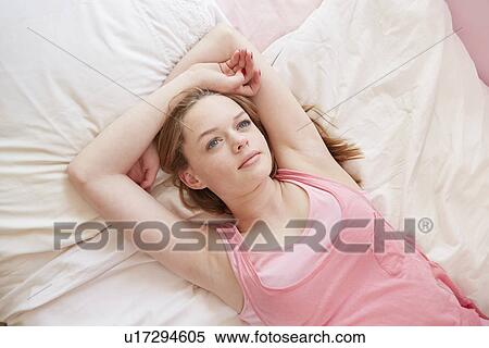 Girl lying on bed gazing upwards View Large Photo Image Stock Photography - Girl lying on bed gazing upwards. Fotosearch