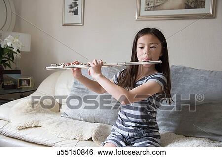 Girl playing the flute on sofa View Large Photo Image Stock Photograph - Girl playing the flute on sofa. Fotosearch
