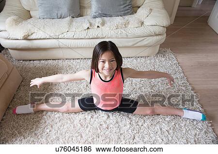 Stock Photograph - Girl practicing gymnastic splits on living room rug. Fotosearch