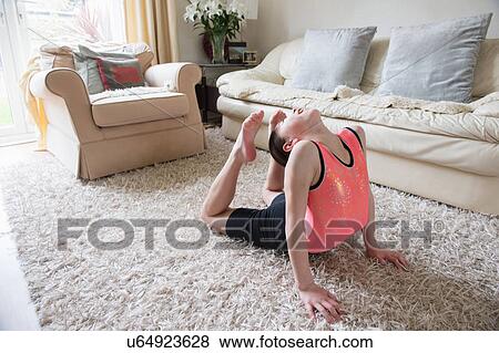 Stock Photo - Girl practicing gymnastics bending over backwards on living room rug. Fotosearch