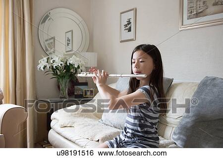 Girl practicing the flute on sofa View Large Photo Image Stock Photograph - Girl practicing the flute on sofa. Fotosearch
