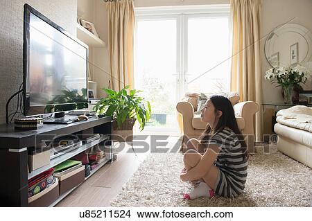 Girl sitting on rug watching the television View Large Photo Image Picture - Girl sitting on rug watching the television. Fotosearch