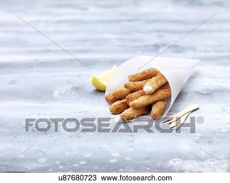 Stock Image - Greaseproof paper cone with lemon sole goujons on steel table. Fotosearch