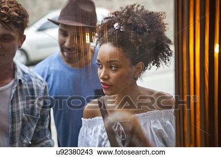 Stock Image - Group of friends looking in shop window. Fotosearch