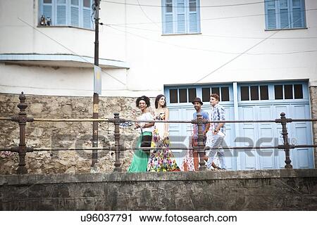 Stock Image - Group of friends walking along walkway together. Fotosearch
