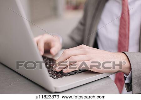 Hands of young city businessman typing on laptop at sidewalk cafe View Large Photo Image Stock Photo - Hands of young city businessman typing on laptop at sidewalk cafe. Fotosearch