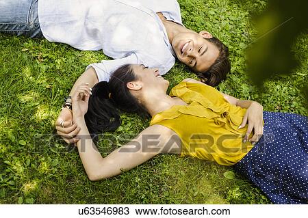 High angle view of young couple lying on grass View Large Photo Image Stock Image - High angle view of young couple lying on grass. Fotosearch