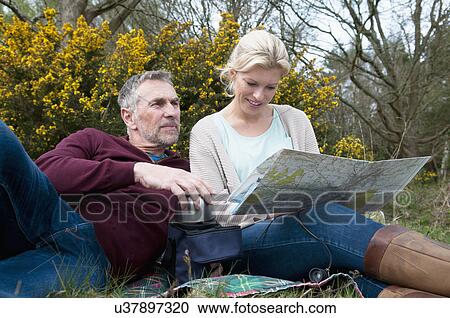 Stock Image - Hiking couple picnicing and reading map. Fotosearch