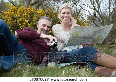 Hiking couple reading map on picnic blanket View Large Photo Image Stock Photo - Hiking couple reading map on picnic blanket. Fotosearch