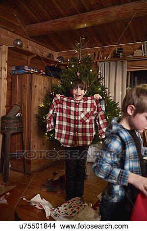 Picture - Joyful boy holding up Christmas shirt. Fotosearch