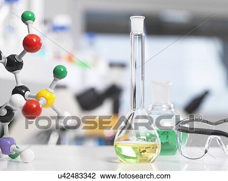 Stock Image -  Laboratory glassware and molecular structure sitting on a lab bench during a experiment. Fotosearch