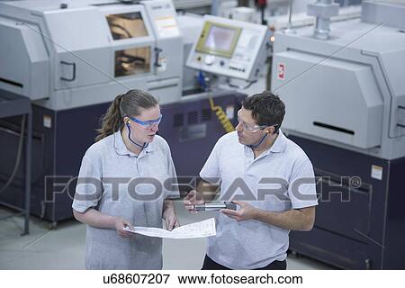 Stock Photo - Male and female engineers discussing manufactured parts. Fotosearch