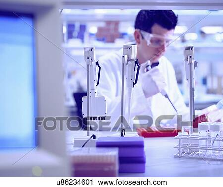 Stock Image - Male worker using pipette in laboratory. Fotosearch