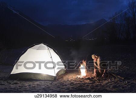 Man by campfire and tent at night View Large Photo Image Stock Photo - Man by campfire and tent at night. Fotosearch