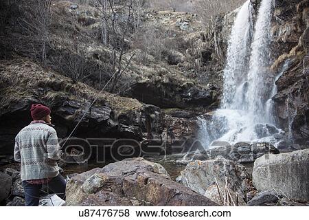 Stock Photo - "Man fishing by waterfall, River Toce, Premosello, Verbania, Piedmonte, Italy". Fotosearch