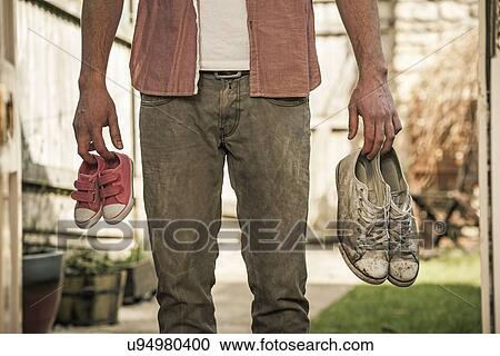 Man holding shoes outside an open door View Large Photo Image Stock Image - Man holding shoes outside an open door. Fotosearch