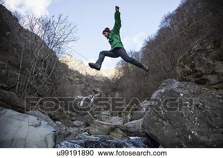 Stock Image - "Man jumping over Toce River, Premosello, Verbania, Piedmonte, Italy". Fotosearch