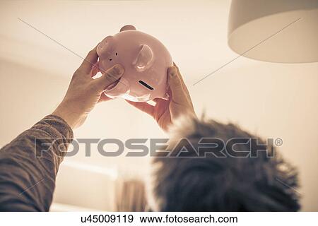 Stock Photo - Man looking up at piggy bank. Fotosearch