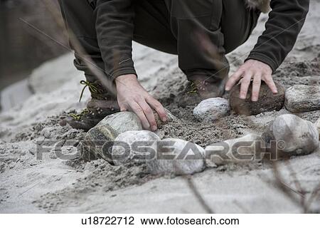 Man making campfire with rocks View Large Photo Image Stock Image - Man making campfire with rocks. Fotosearch