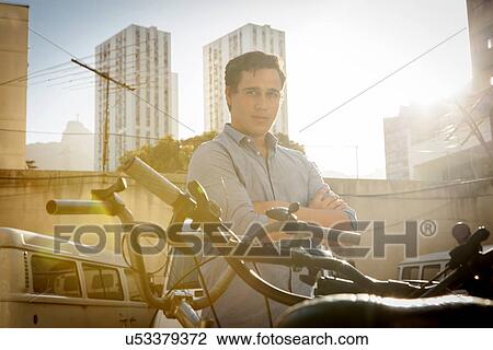 Man standing beside bicycles View Large Photo Image Stock Image - Man standing beside bicycles. Fotosearch