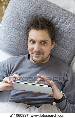 Man using digital tablet on bed View Large Photo Image Stock Photo - Man using digital tablet on bed. Fotosearch