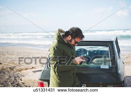 "Man with vintage car on beach reading smartphone texts, Sorso, Sassari, Sardinia, Italy" View Large Photo Image Stock Image - "Man with vintage car on beach reading smartphone texts, Sorso, Sassari, Sardinia, Italy". Fotosearch