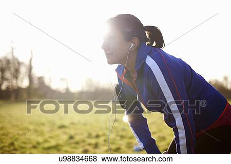 Stock Photo - Mature female runner in field taking a break. Fotosearch