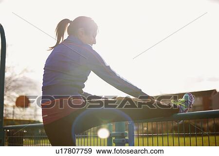 Mature female runner stretching leg on park fence View Large Photo Image Stock Photo - Mature female runner stretching leg on park fence. Fotosearch